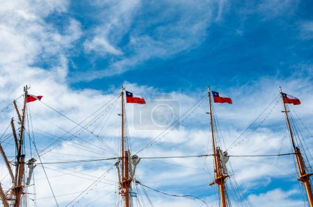 Foto de Banderas de la República de Chile, sobre cuatro mástiles ondeando con el cielo azul como fondo. - Imagen libre de derechos