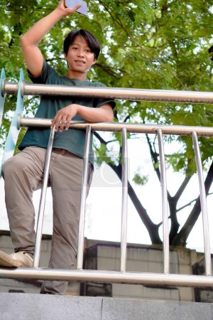 bottom view of a handsome man standing with his arms outstretched on the safety fence. 