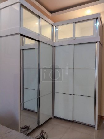 wardrobe with L-shaped glass doors placed in the corner of the room.