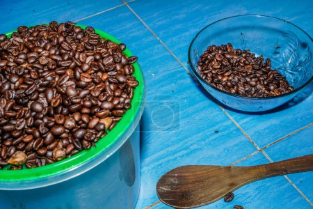 Photo for Black coffee beans in a bowl on the green floor. - Royalty Free Image