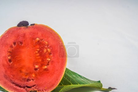 Guava isolated. Collection of red fleshed guava fruit with yellowish green skin on a leaf isolated on a white background.