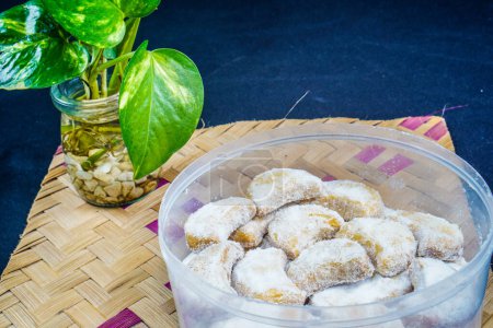 pastel blanco nieve aislado en una mesa tejida de bambú con un fondo negro. pastel de luna creciente con salpicaduras de azúcar granuladas aisladas sobre un fondo negro. Concepto de pastel Eid.