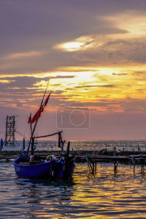 Fischerboote an der Seebrücke mit einem isolierten orangefarbenen Abendhimmel mit freiem Platz zum Kopieren.