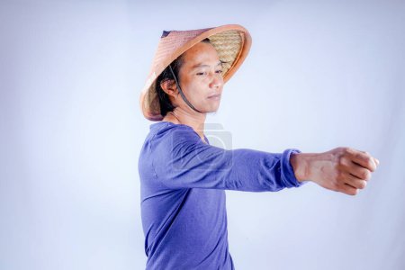 asiatischer Mann mit geflochtenem Bambushut, der seine Hand auf leerem Raumhintergrund für Werbung ausstreckt.