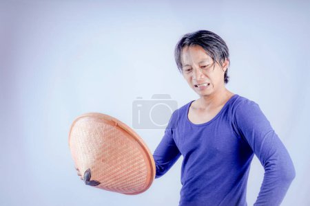 Javanese farmer holding a woven bamboo hat used for fanning, white background with empty space for advertising.