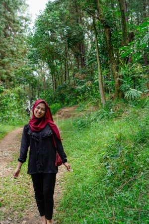 Frau läuft allein im Gummiwald mit steinigen Feldwegen, Bäume Hintergrund für Werberaum