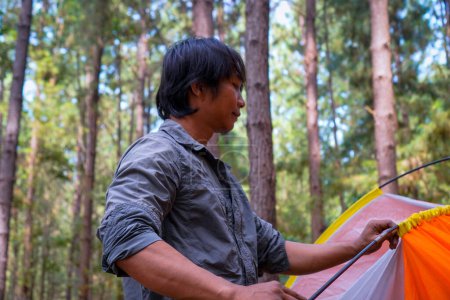 El hombre javanés está instalando una tienda en un bosque de caucho, el concepto de recreación en el bosque