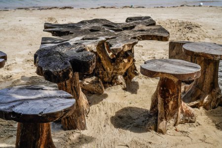 Ein antiker Holztisch und Stühle am Strand Sand vor dem Hintergrund des blauen Meeres mit leeren Werbeflächen.