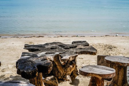 Ein antiker Holztisch und Stühle am Strand Sand vor dem Hintergrund des blauen Meeres mit leeren Werbeflächen.