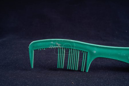 close up of a broken toothed comb on a black background with empty space for photocopying.