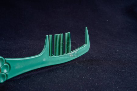 close up of a broken toothed comb on a black background with empty space for photocopying.