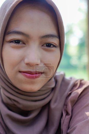 close up of a veiled Javanese woman with a charming smile.