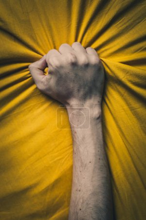 Photo for Man's hand breaking through the yellow fabric. Conceptual image. - Royalty Free Image