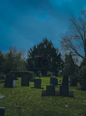 Cemetery with tombstones and green grass under a blue sky.
