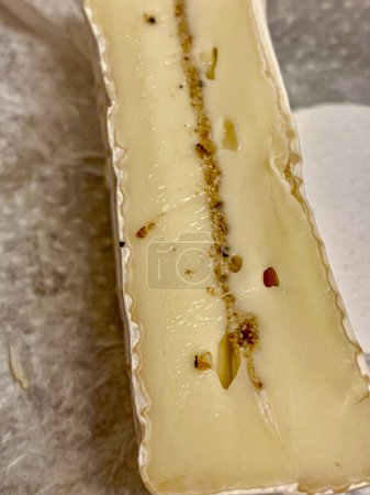 a slice of French cheese cut from cow's milk with white mold and truffle