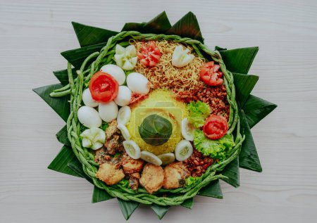 Vista superior del arroz amarillo en forma de cono. En Indonesia llamado "Nasi Tumpeng" Un plato de arroz indonesio festivo con guarniciones. Arroz Tumpeng en bandeja tejida de bambú.