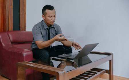 Young businessman focused working on laptop, using video call with client on laptop. Young Indonesian man concentrating on giving online education class lectures, consulting with customers.