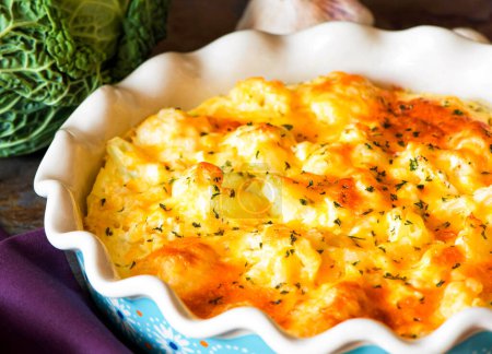 Cauliflower casserole with cheese and milk sauce in a baking dish.
