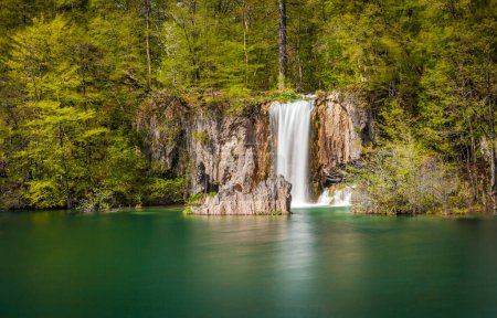 Foto de Hermosa cascada sumergiéndose en el estanque de esmeralda cristalina, Parque Nacional de los Lagos de Plitvice, Croacia. Larga exposición. - Imagen libre de derechos