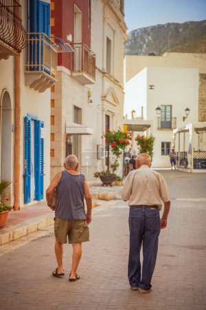 Foto de Dos ancianos caminando en la calle principal del pueblo de Marettimo, islas Egadi, Italia - Imagen libre de derechos