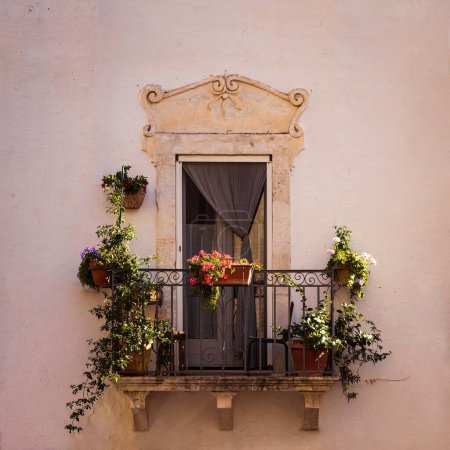 Foto de Hermoso balcón adornado con flores y plantas en un palacio barroco histórico, Ostuni, Brindisi, Italia - Imagen libre de derechos
