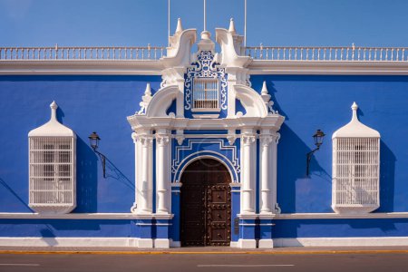 Foto de Arquitectura azul tradicional con barandas de ventanas pintadas de blanco y puerta principal adornada, Trujillo, Perú - Imagen libre de derechos