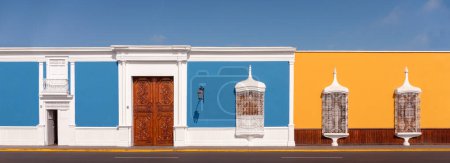 Foto de Arquitectura colonial tradicional con barandillas blancas pintadas, delicadas ventanas, puertas de madera con incrustaciones y paredes de colores pastel, Trujillo, Perú - Imagen libre de derechos
