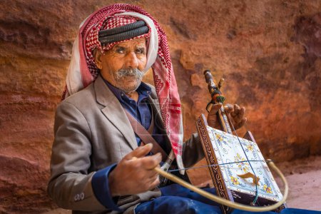 Foto de Viejo hombre beduino tocando una rababa de una sola cuerda en la antigua ciudad de Petra, Jordania - Imagen libre de derechos
