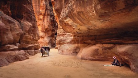 Téléchargez les photos : Le Siq avec une charrette tirée par des chevaux pour transporter les touristes et un joueur de rababa, Petra, Jordanie - en image libre de droit