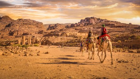 Foto de Turistas montando camellos hacia la Puerta de Temenos en la calle Colonnaded, Petra, Jordania. - Imagen libre de derechos