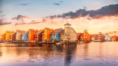 Téléchargez les photos : Beaux bâtiments colorés réfléchissant sur l'eau sous un coucher de soleil spectaculaire, Reitdiephaven, Groningue, Pays-Bas - en image libre de droit