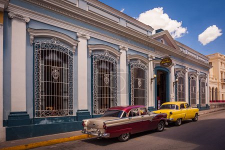 Foto de Coches americanos de época frente a edificios coloniales en Santa Clara, Cuba - Imagen libre de derechos