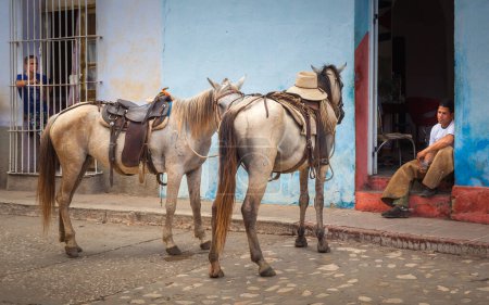 Photo for A Cuban cowboy rests on home doorstep in a sweltering summer day after a touristic tour in the rainforest, Trinidad, Cuba - Royalty Free Image