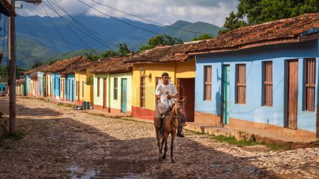 Photo for Man riding a horse in cobblestones street with colorful  colonial houses, Trinidad, Cuba - Royalty Free Image