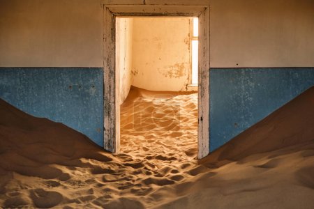 Téléchargez les photos : Intérieur d'un bâtiment abandonné à Kolmanskop, Namibie, englouti par le sable et illuminé par la lumière chaude du désert du Namib. Fondée en 1908 pour l'exploration du diamant, la ville a été abandonnée en 1956. - en image libre de droit