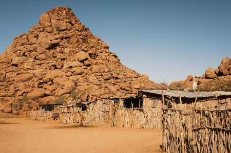 Houses in a Damara tribe village, near Twyfelfontein, Kunene, Namibia. Houses are constructed with tree branches and mud and covered with corrugated metal due to lack of straw.
