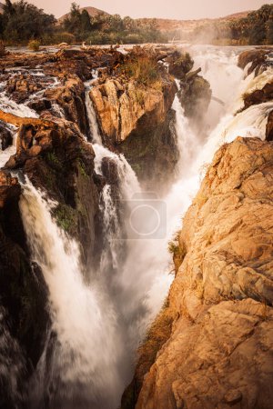 Epupa Falls, Kunene Region, Namibia, in warmem, goldenem Licht. Epupa Falls ist eine Reihe großer Wasserfälle, die vom Kunene River an der Grenze zwischen Angola und Namibia gebildet werden..