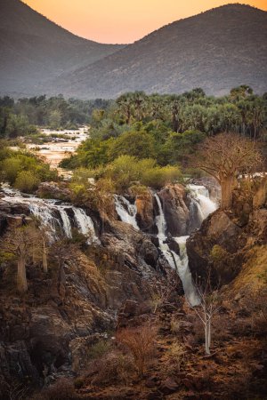 Photo for Epupa Falls, Kunene Region, Namibia, in warm sunrise light. Epupa Falls is a series of large waterfalls formed by the Kunene River on the Angola-Namibia border. - Royalty Free Image