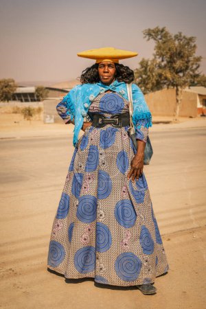 Foto de Retrato completo de la mujer Herero, Opuwo, Namibia. Originalmente Himba, fueron evangelizados por misioneros alemanes y comenzaron a usar ropa de estilo victoriano llamada Hererotracht.. - Imagen libre de derechos
