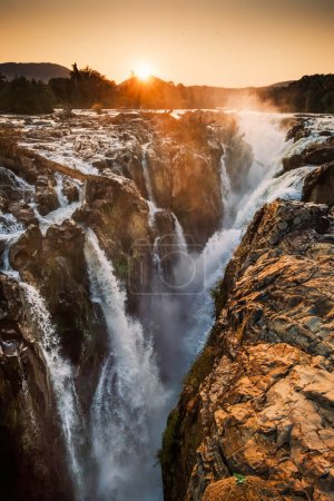 Epupa Falls, Kunene Region, Namibia, in warm sunrise light. Epupa Falls is a series of large waterfalls formed by the Kunene River on the Angola-Namibia border.