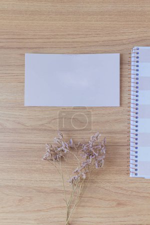 Téléchargez les photos : Espace de travail avec carnet rose pâle, feuille de papier vierge sur fond en bois. Couché plat, vue du dessus - en image libre de droit