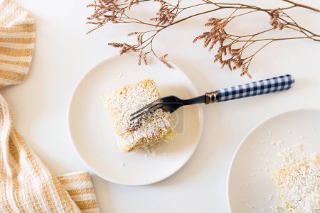 Téléchargez les photos : Vue du dessus du gâteau à la noix de coco fait maison pour le petit déjeuner. composition confortable beige avec des fleurs séchées - en image libre de droit