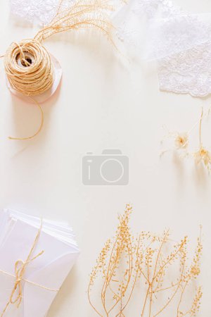 Foto de Composición de invitaciones de boda beige. Sobres blancos, flores secas, encaje textil, cuerda de sisal sobre fondo blanco. Asiento plano, vista superior. Estacionario neutro. - Imagen libre de derechos