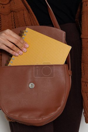 Photo for Young pretty woman in brown sweater holding a planner. Fall, autumn fashion composition. - Royalty Free Image