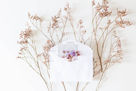 Téléchargez les photos : Enveloppe d'invitation de mariage, fleurs lilas sur fond blanc. Couché plat, vue du dessus. - en image libre de droit