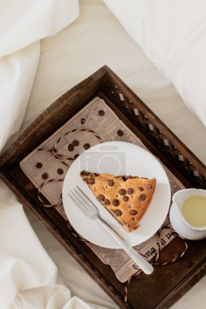 Téléchargez les photos : Tranche de tarte à biscuits dans un plateau en bois sur le lit. Concept petit déjeuner. - en image libre de droit