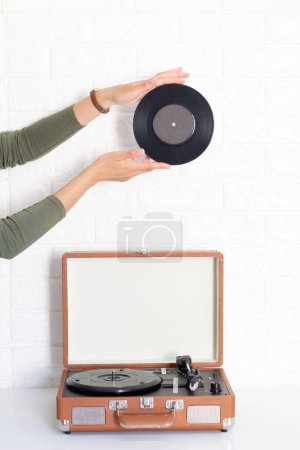Photo for Female hands holding vinyl record over the Phonograph on white background. Aesthetic vintage concept. - Royalty Free Image