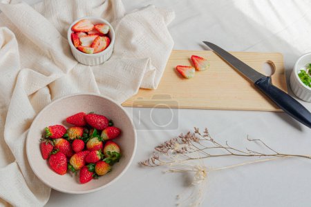 Photo for Strawberries in a bowl and cutting board on white and styled background. - Royalty Free Image