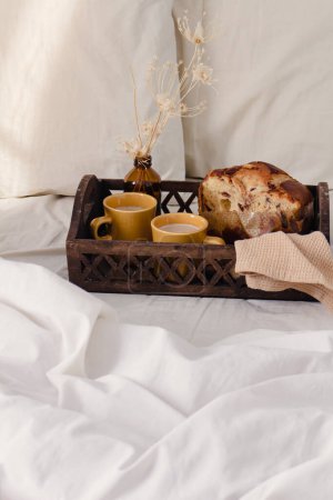 Photo for Breakfast on dark wooden vintage tray in bed with light beige sheet and pillows. romantic morning concept. - Royalty Free Image