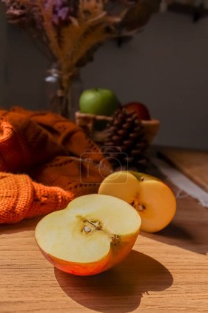 Photo for Juicy apple slices with brown sweater and pine cone on wooden background - Royalty Free Image